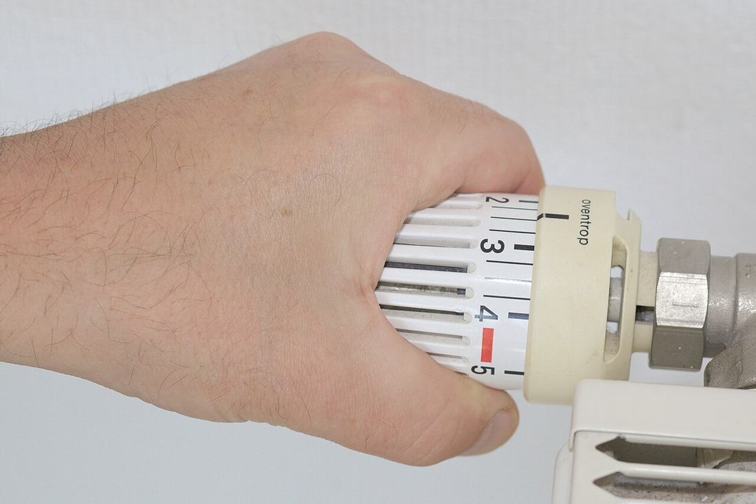 Hand an einem Thermostat